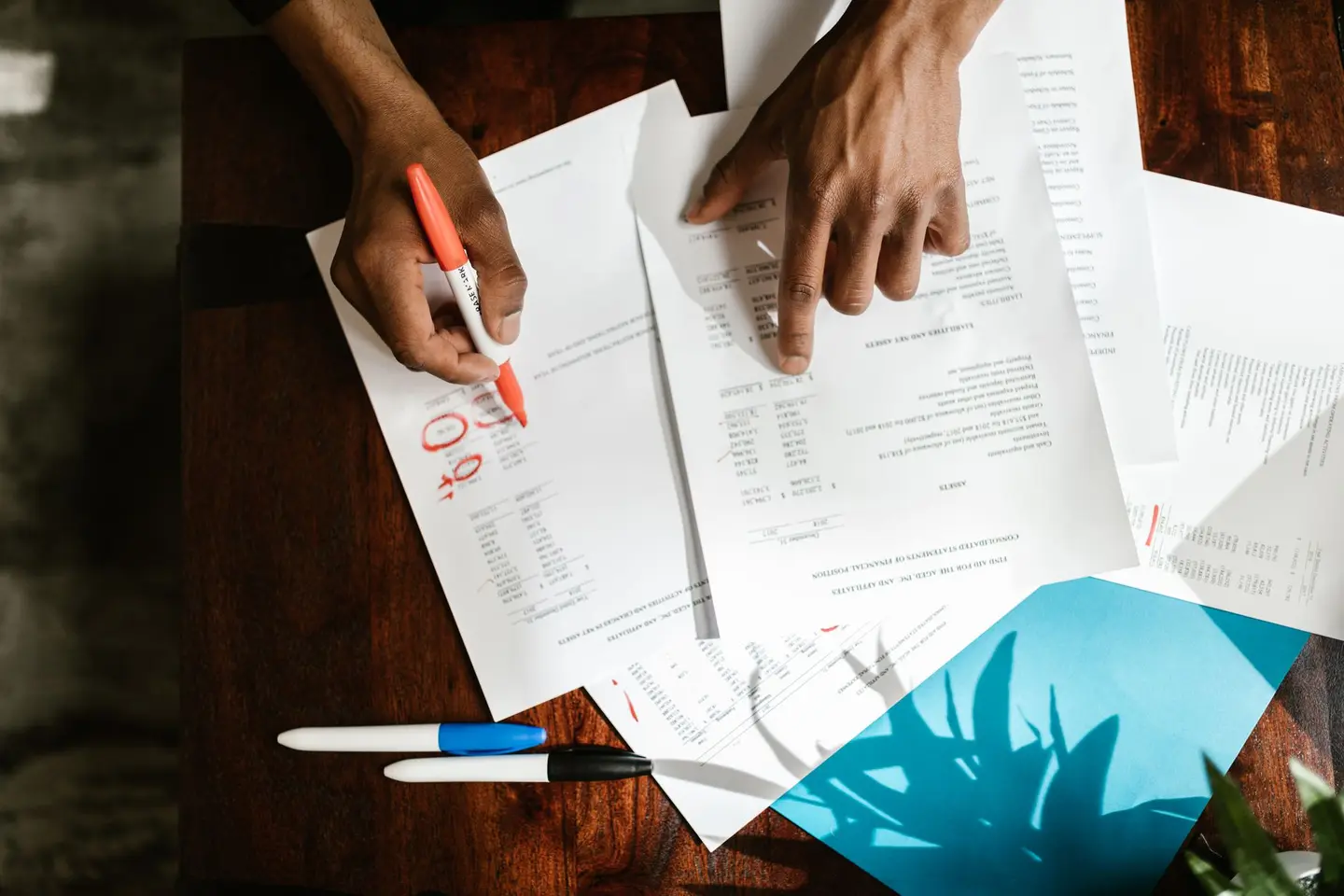 Two people reviewing printed documents marked up with a red pen