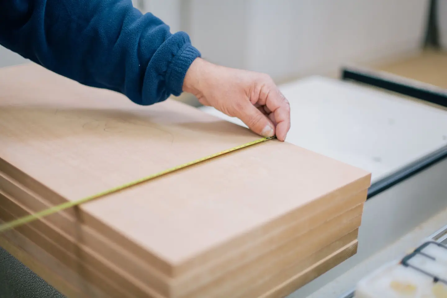 A tape measure stretched across a stack of timber boards in a workshop