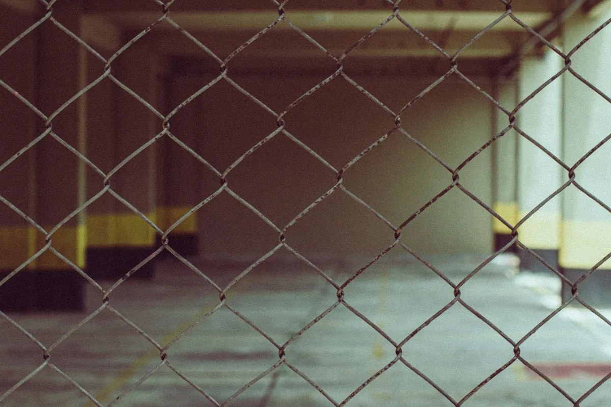 An empty concrete building floor seen through a chain-link fence