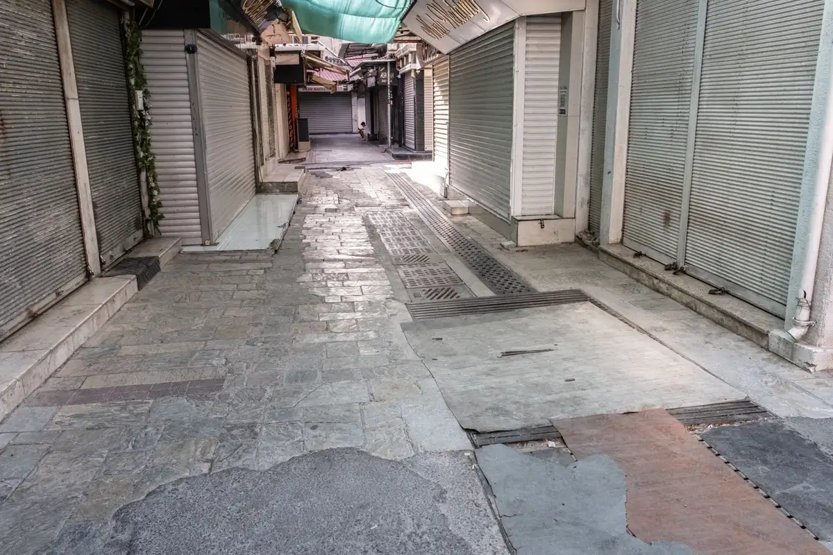 An empty lane of shops with their roller shutters closed