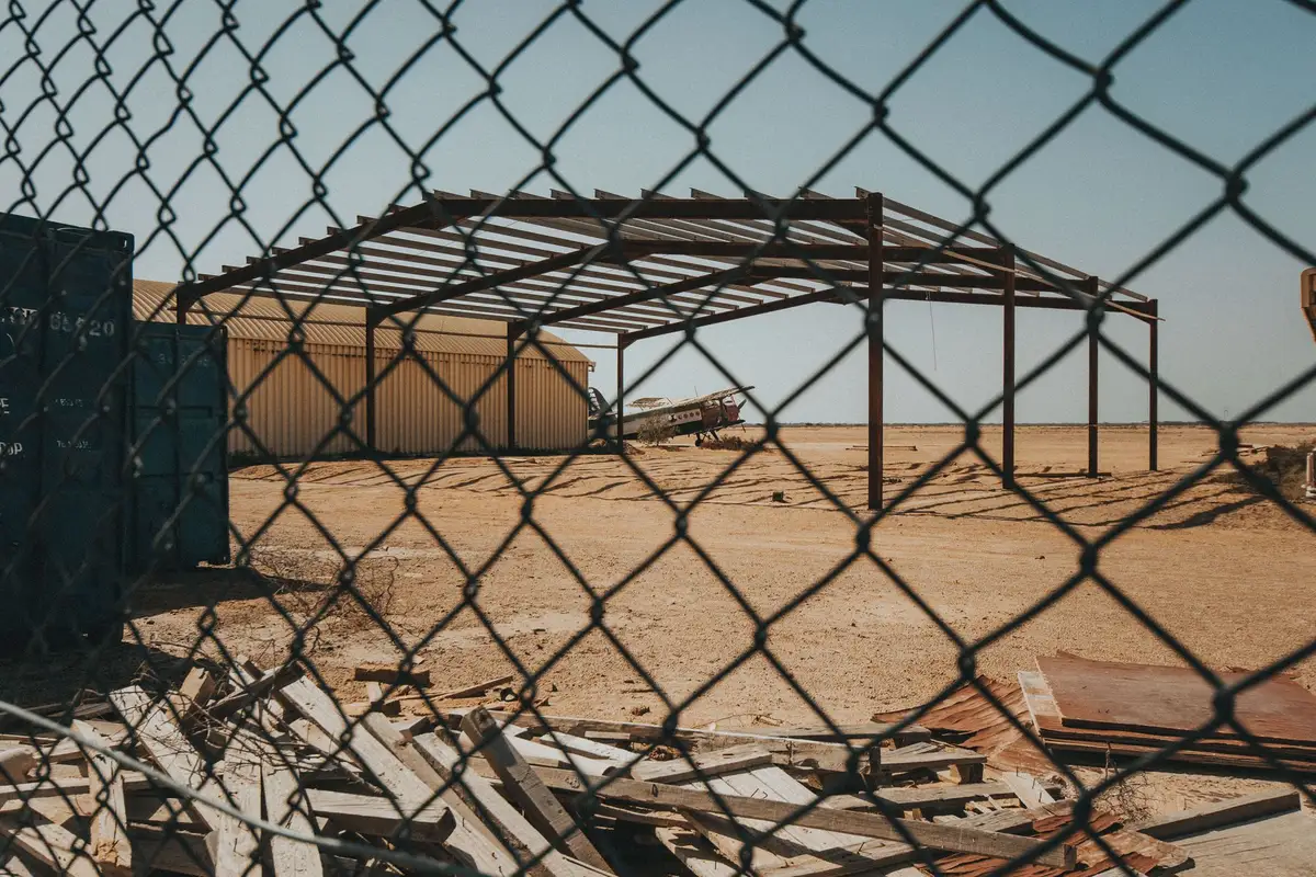 An empty construction site with a bare steel frame behind a chain-link fence