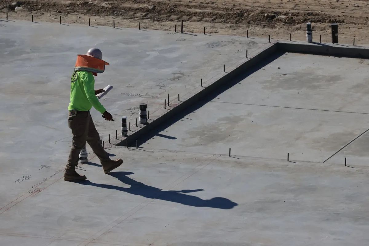 A worker walking across a finished concrete slab on a building site