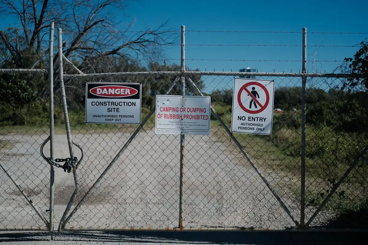 A locked gate on a vacant construction site with danger and no entry signs