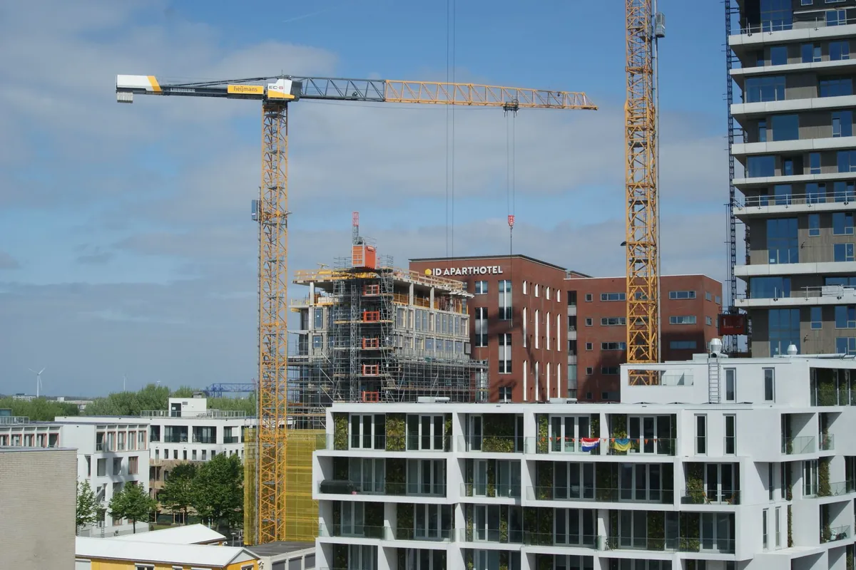 Tower cranes above residential buildings under construction on a clear day