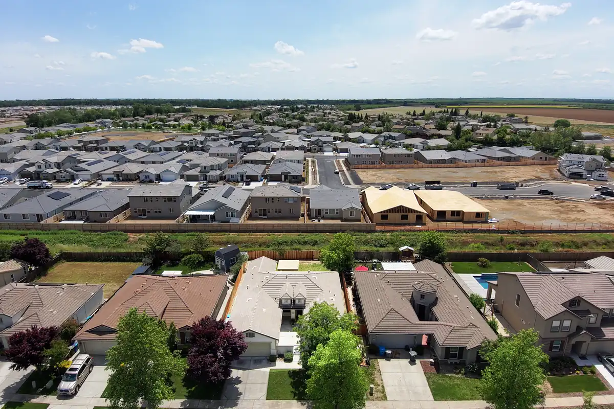 An aerial view of a suburb with new houses being built on its edge