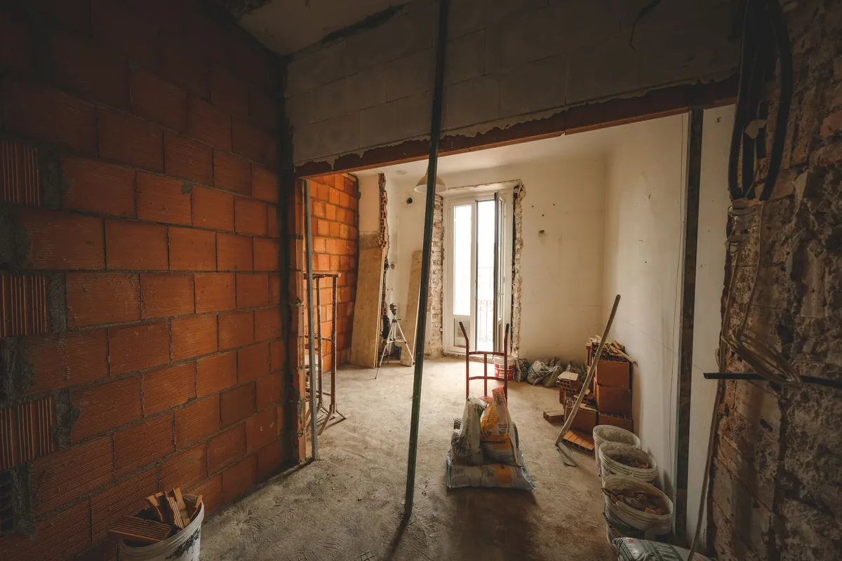 A room under construction with exposed brick walls and building materials on the floor