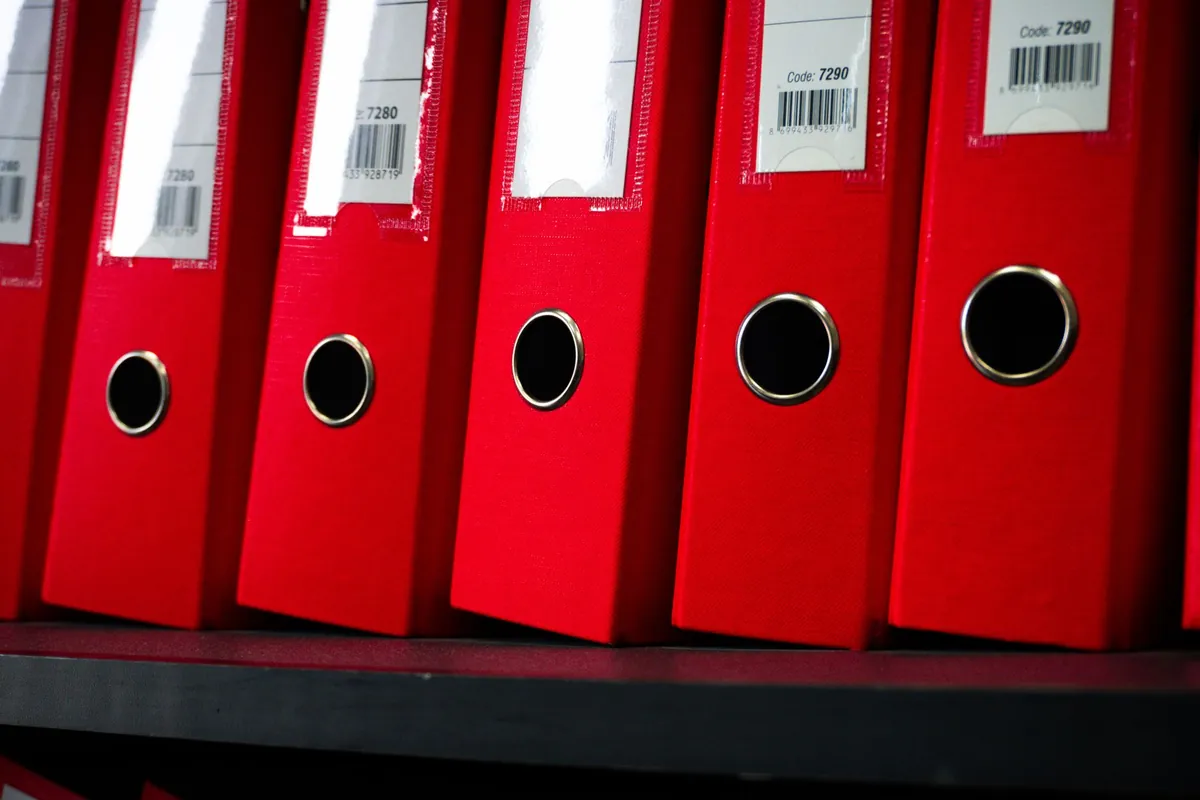 A row of red office binders on a shelf