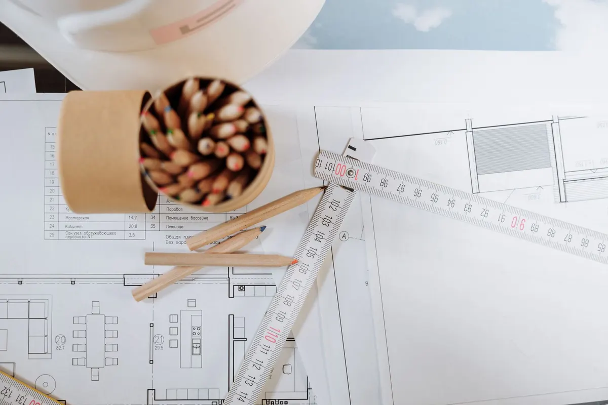 Architectural floor plans with a folding ruler and a pot of pencils