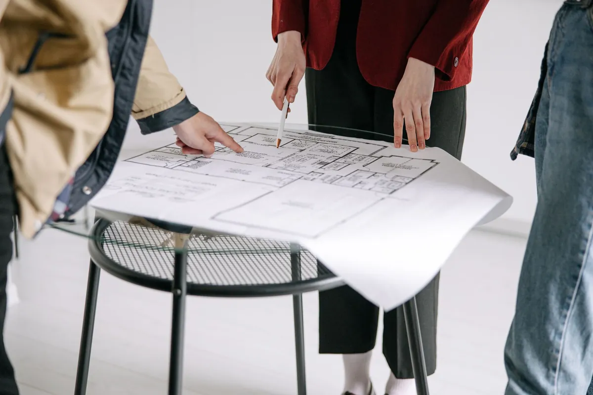 People reviewing a set of architectural plans spread on a table