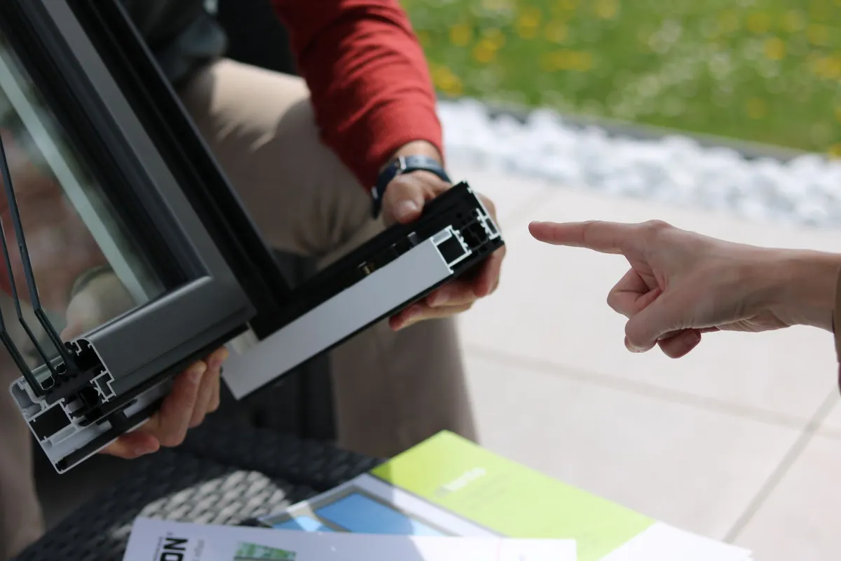 Two people examining a section of aluminium window frame